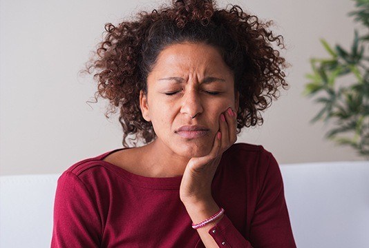 Woman holding cheek in pain