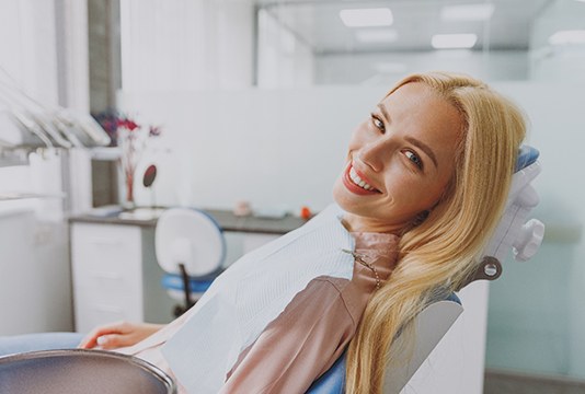 Blonde female dental patient sitting back in chair and smiling