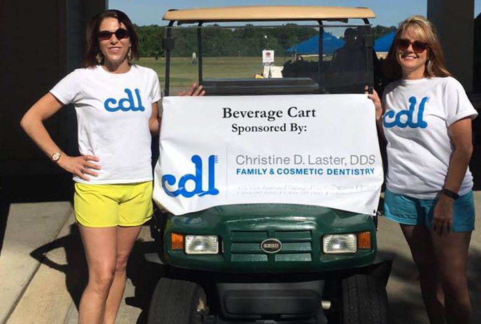 Two team members by a golf cart at community event