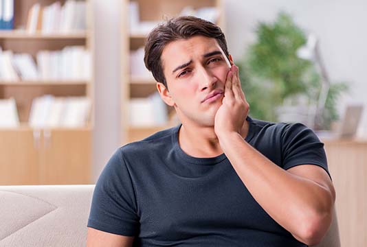 Man with a toothache in Raleigh holding his cheek