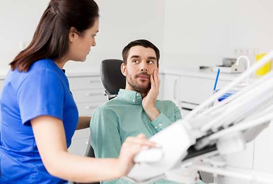 Man listening to Raleigh emergency dentist and holding his cheek