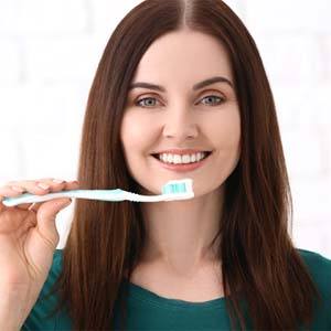 Woman with brown hair brushing her teeth