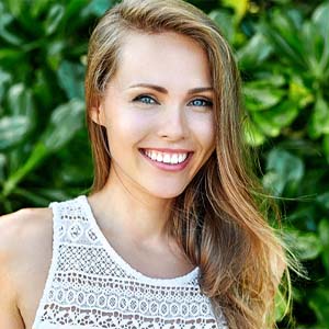 Woman smiling with green leaves in background