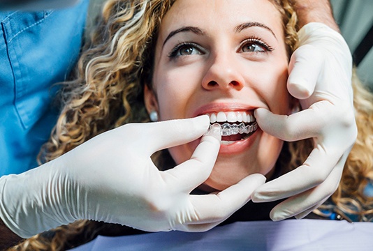 Dentist placing clear aligner on smiling patient