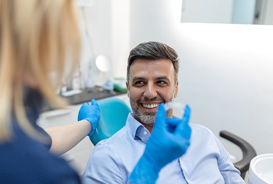 Patient smiling at dentist holding clear aligner