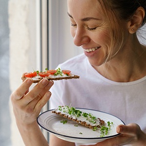 Woman smiling while eating healthy meal at home