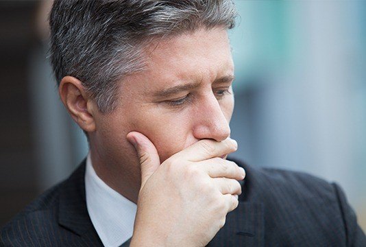 Man in business suit covering his mouth