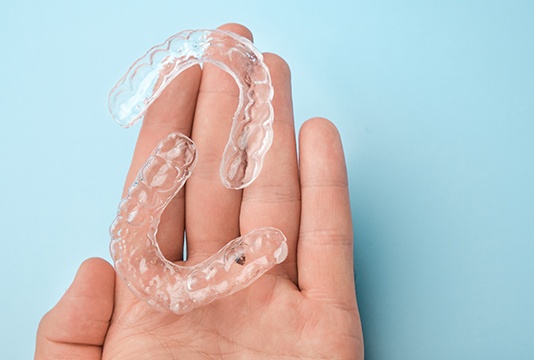 Person holding SureSmile aligners