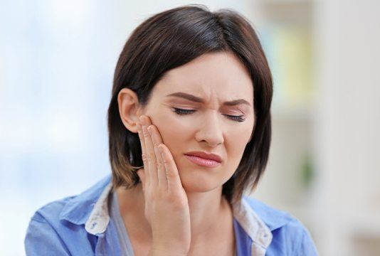 Woman holding jaw in pain