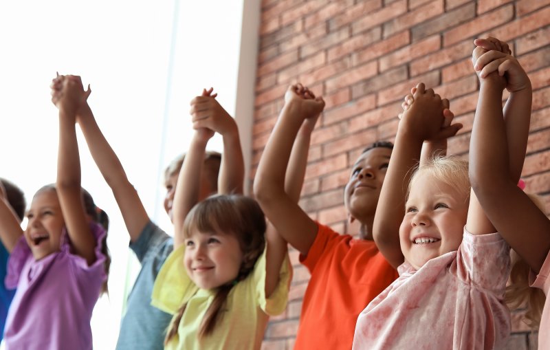 A group of children smiling with good dental hygiene and holding hands