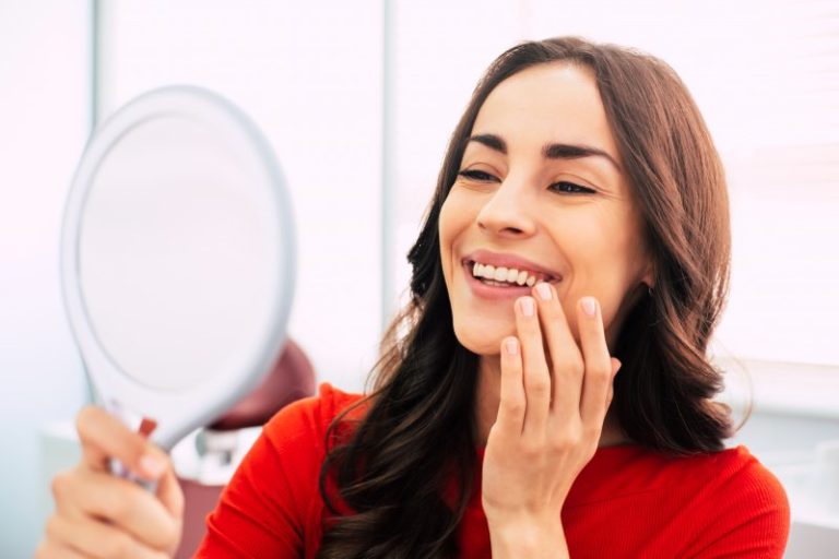 Woman looking at her dental implant and smiling